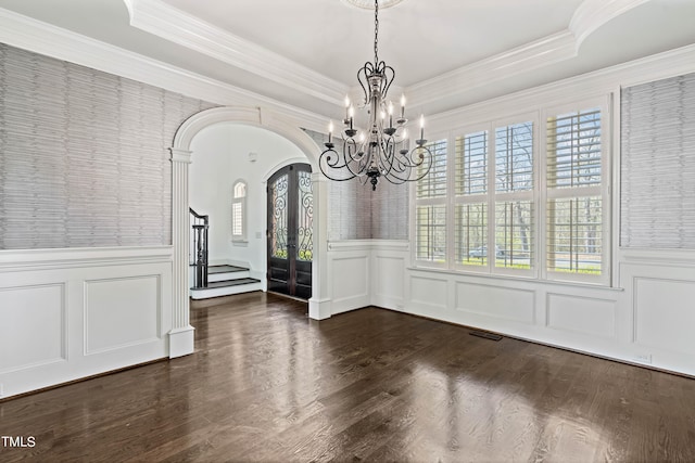 unfurnished room featuring plenty of natural light, dark hardwood / wood-style flooring, a notable chandelier, and a tray ceiling