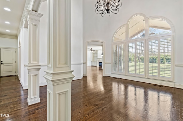 interior space featuring a chandelier, crown molding, decorative columns, and dark hardwood / wood-style flooring