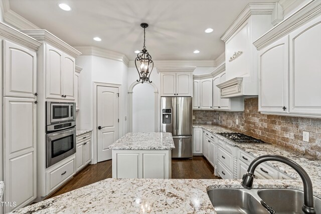 kitchen with white cabinets, a kitchen island, stainless steel appliances, pendant lighting, and sink