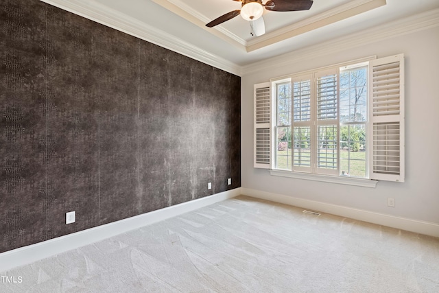 carpeted spare room featuring ceiling fan, ornamental molding, and a tray ceiling