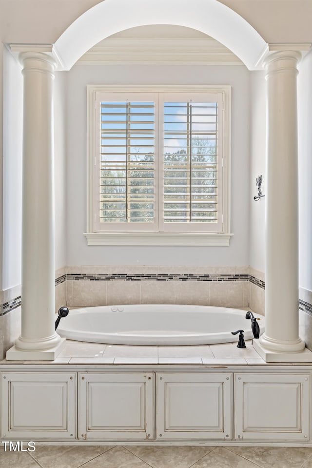 bathroom featuring ornate columns, a bathing tub, and tile floors