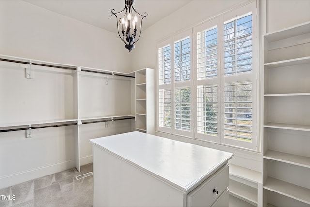 spacious closet featuring an inviting chandelier and light colored carpet