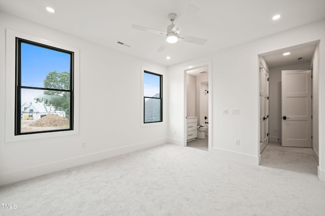 unfurnished bedroom featuring light carpet, connected bathroom, and ceiling fan