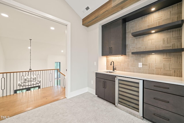 bar featuring sink, beverage cooler, decorative light fixtures, light carpet, and a notable chandelier