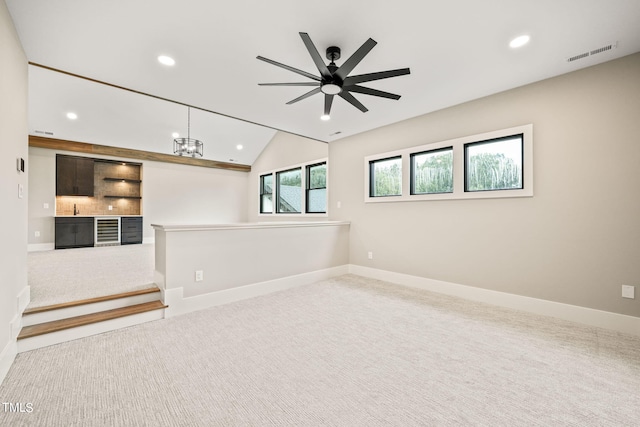 carpeted empty room featuring ceiling fan with notable chandelier, lofted ceiling, and sink