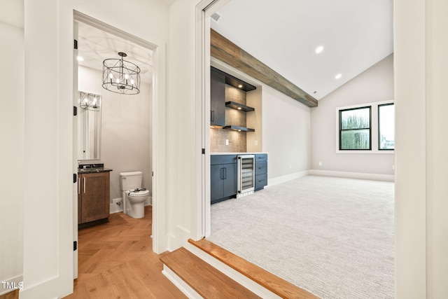 hallway with beverage cooler, a chandelier, vaulted ceiling, and light parquet flooring