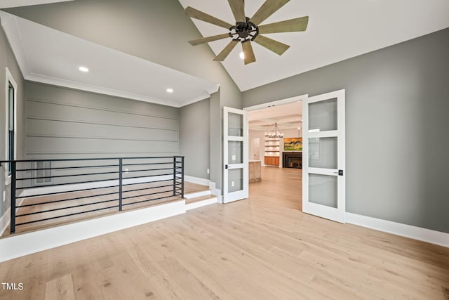 unfurnished room featuring ceiling fan with notable chandelier, vaulted ceiling, light hardwood / wood-style flooring, and ornamental molding