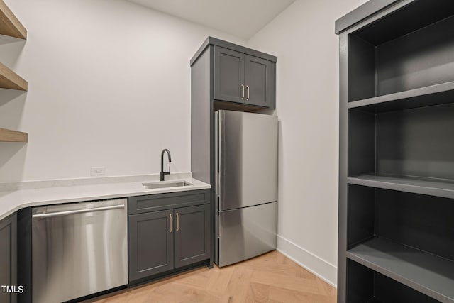 kitchen featuring stainless steel appliances, sink, light parquet flooring, and gray cabinetry