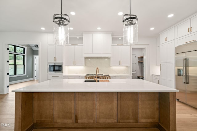 kitchen with white cabinetry, built in appliances, and a spacious island