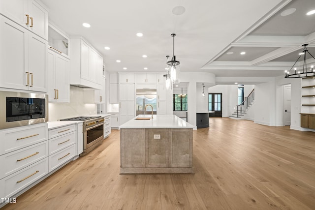 kitchen featuring a large island, decorative light fixtures, white cabinetry, appliances with stainless steel finishes, and light hardwood / wood-style floors