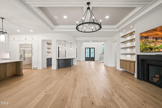 unfurnished living room with light wood-type flooring, ornamental molding, a tray ceiling, and built in features