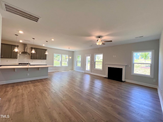 unfurnished living room featuring ceiling fan with notable chandelier and dark hardwood / wood-style flooring