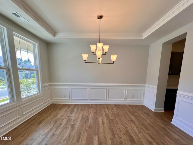 unfurnished room with a raised ceiling, ornamental molding, a chandelier, and wood-type flooring