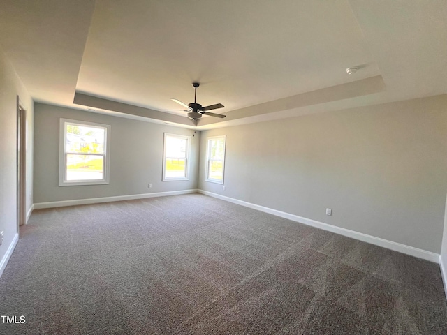 carpeted spare room featuring ceiling fan and a raised ceiling