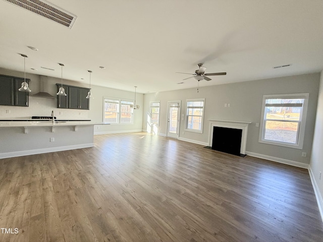 unfurnished living room featuring dark hardwood / wood-style flooring, ceiling fan, and sink