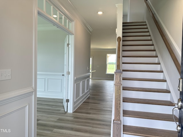 staircase with wood-type flooring and crown molding