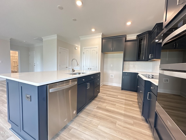 kitchen featuring appliances with stainless steel finishes, decorative backsplash, sink, ornamental molding, and a kitchen island with sink