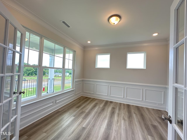 unfurnished room featuring plenty of natural light, hardwood / wood-style floors, crown molding, and french doors