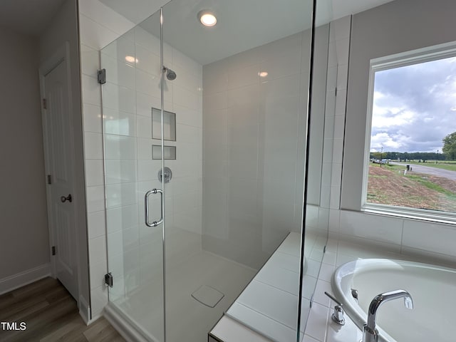 bathroom featuring a wealth of natural light, shower with separate bathtub, and hardwood / wood-style flooring