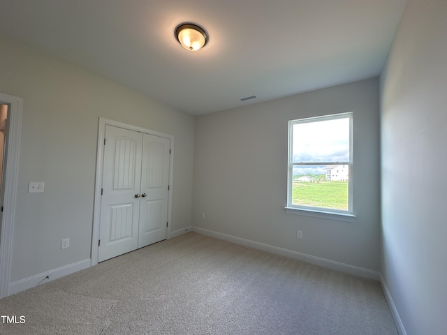 unfurnished bedroom with a closet and light colored carpet