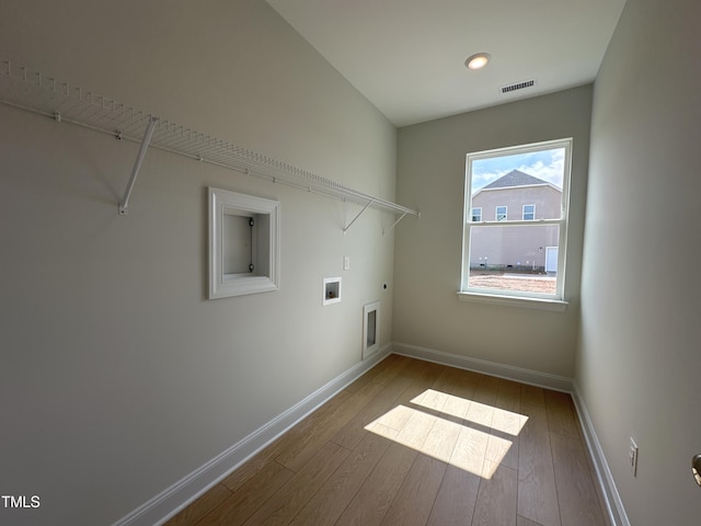 washroom with hookup for an electric dryer, hookup for a washing machine, and hardwood / wood-style floors