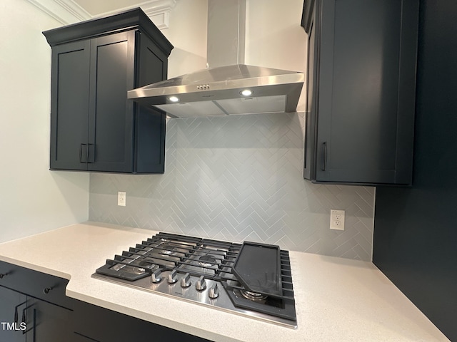 kitchen with tasteful backsplash, wall chimney exhaust hood, ornamental molding, and stainless steel gas stovetop