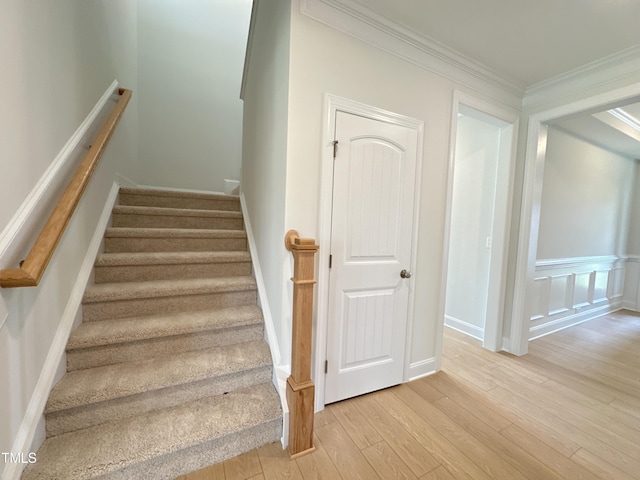 stairway with hardwood / wood-style flooring and crown molding