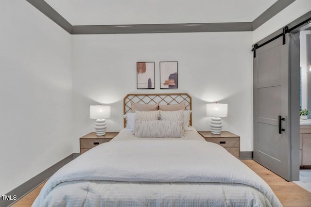 1312 Hunting Ridge Rd, Raleigh, NC 27615 - bedroom with a barn door, wood finished floors, and baseboards