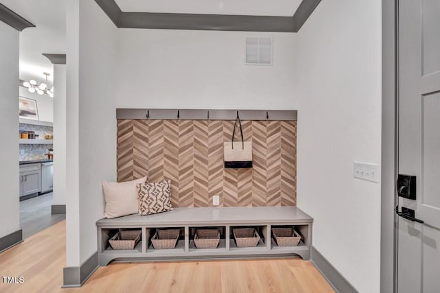 mudroom featuring crown molding, an inviting chandelier, and hardwood / wood-style flooring