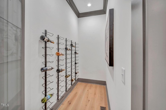 wine area featuring wood-type flooring and ornamental molding