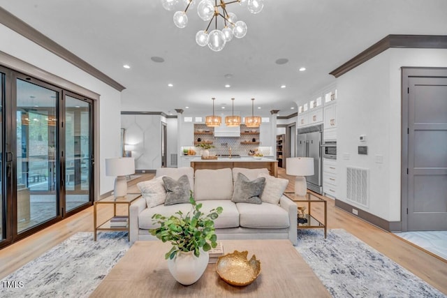 1312 Hunting Ridge Rd, Raleigh, NC 27615 - living area featuring light wood finished floors, a chandelier, recessed lighting, crown molding, and baseboards