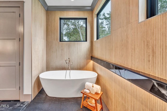 bathroom with tile patterned floors, a washtub, and a healthy amount of sunlight