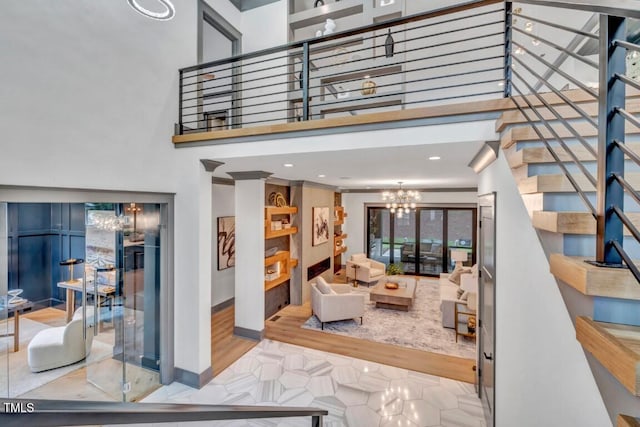 1312 Hunting Ridge Rd, Raleigh, NC 27615 - living room featuring stairway, a chandelier, wood finished floors, a high ceiling, and baseboards