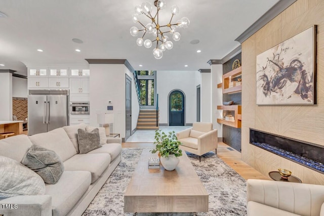 1312 Hunting Ridge Rd, Raleigh, NC 27615 - living room with a tiled fireplace, light wood-style flooring, a chandelier, crown molding, and stairway