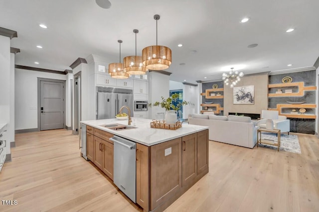 1312 Hunting Ridge Rd, Raleigh, NC 27615 - kitchen featuring ornamental molding, built in appliances, a sink, light wood finished floors, and a kitchen island with sink