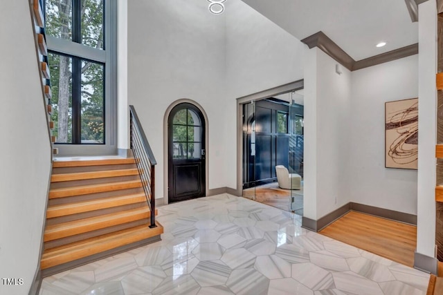 1312 Hunting Ridge Rd, Raleigh, NC 27615 - tiled foyer featuring stairs, baseboards, a high ceiling, and arched walkways