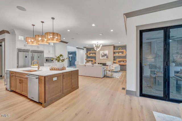 1312 Hunting Ridge Rd, Raleigh, NC 27615 - kitchen featuring a sink, stainless steel appliances, light wood-style flooring, light countertops, and a kitchen island with sink