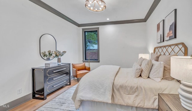 bedroom featuring light wood-type flooring, ornamental molding, and an inviting chandelier