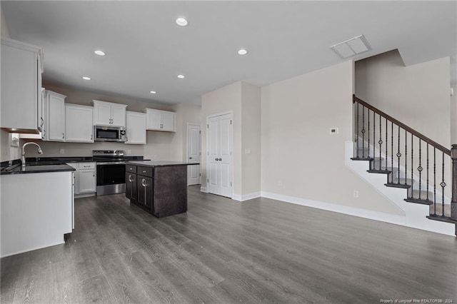 kitchen with dark wood-type flooring, sink, white cabinetry, appliances with stainless steel finishes, and a kitchen island