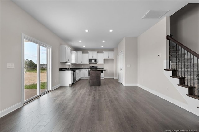 kitchen with dark wood-type flooring, sink, white cabinetry, appliances with stainless steel finishes, and a kitchen island