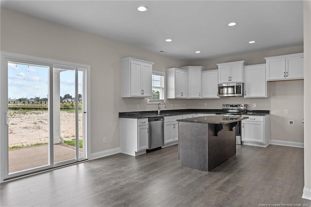 kitchen with appliances with stainless steel finishes, a center island, dark wood-type flooring, and white cabinets