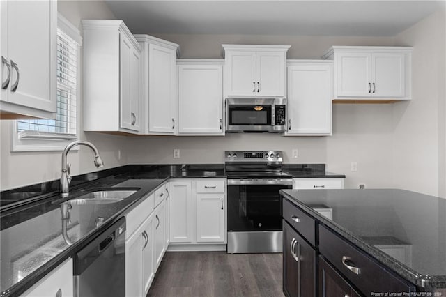 kitchen featuring dark stone countertops, stainless steel appliances, and white cabinets