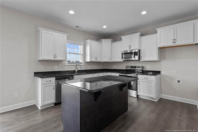 kitchen with white cabinetry, a kitchen island, a breakfast bar, and appliances with stainless steel finishes