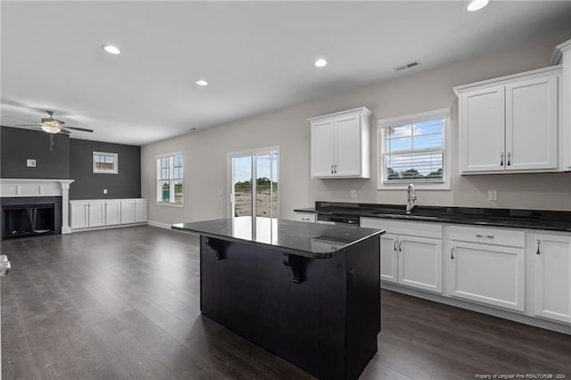 kitchen featuring a breakfast bar, dark hardwood / wood-style floors, white cabinetry, sink, and a center island