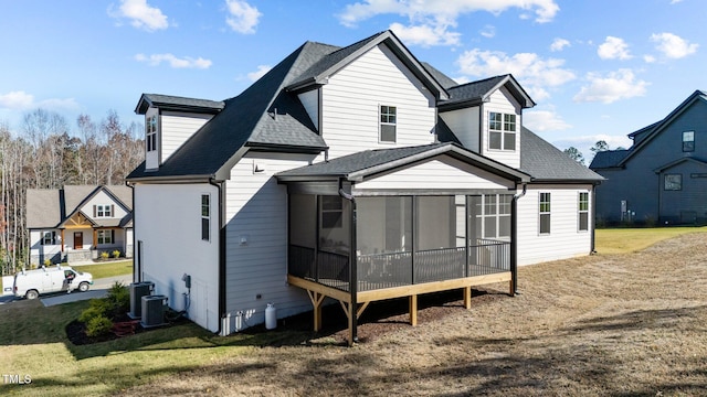 rear view of house with a lawn, a sunroom, and central air condition unit