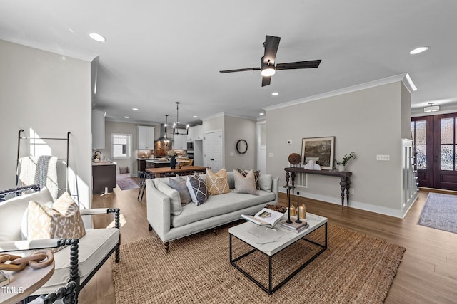 living room with french doors, crown molding, ceiling fan, and light hardwood / wood-style flooring