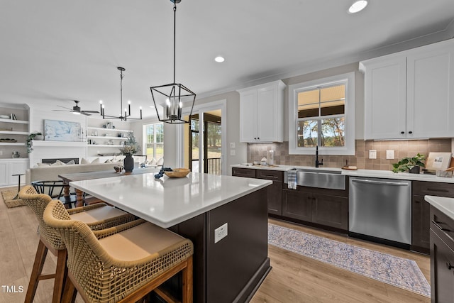 kitchen featuring a kitchen bar, sink, decorative light fixtures, dishwasher, and a kitchen island