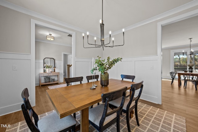 dining area with hardwood / wood-style flooring, ornamental molding, and a notable chandelier