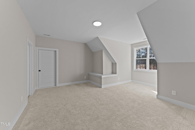 additional living space featuring light colored carpet and lofted ceiling