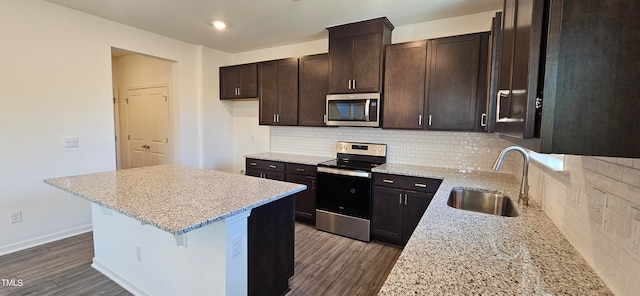 kitchen featuring light stone counters, appliances with stainless steel finishes, sink, and dark hardwood / wood-style flooring